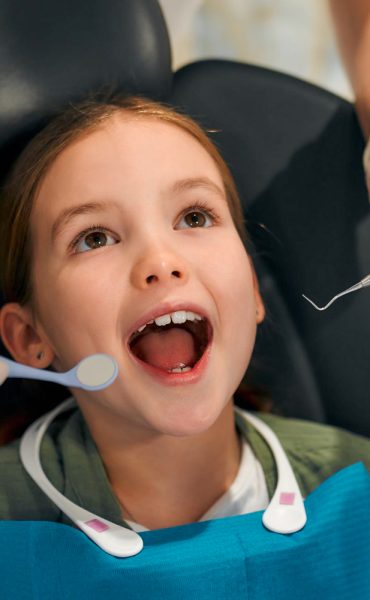 crianca-menina-sentada-em-uma-cadeira-odontologica-abrindo-a-boca-no-exame-por-um-dentista-pediatrico-em-uma-clinica-odontologica-odontologia-e-cuidados-com-os-dentes-de-leite